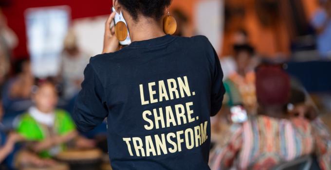 woman with shirt that reads "learn, share, transform"